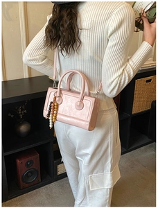 Pink baguette bag with beaded charm accessory shown in a stylish lifestyle setting