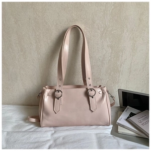 Detail of light pink PU leather handbag with silver rings, rivets and a modern design