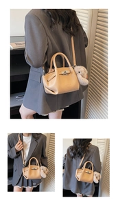 Detail view of khaki pebbled leather handbag with metal turn-lock and plush bunny charm