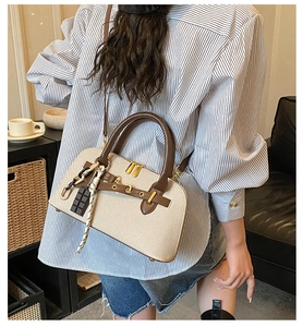 Détail du sac coquillage en toile bicolore avec bordure en cuir marron et breloque tissée