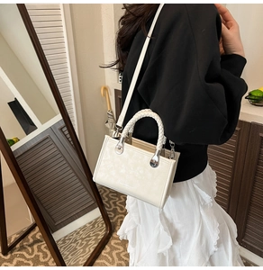Chic cream white mini crossbody bag with unique woven top handle shown on a model