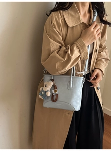 Detail of light blue bucket bag with cute bear charm and adjustable shoulder strap