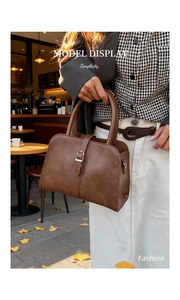 Close-up of brown vintage handbag with silver buckle detail in a street cafe setting