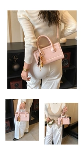 Pink baguette bag detail with wooden bead charm and detachable shoulder strap on cream outfit