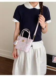 Detail of light purple plaid handbag with pink bow patterns and white rabbit plush charm