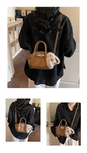 Detail of brown litchi leather tote with metal twist lock and cute rabbit charm