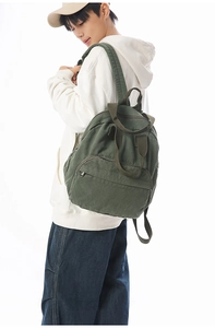 Detail view of large dark green canvas backpack with side straps on model