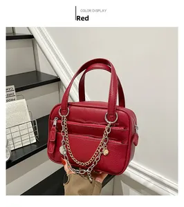 Close-up of red leather handbag with litchi texture and metallic heart charm detail