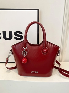 Elegant dark red leather bucket bag with top handle and metallic logo on white stand