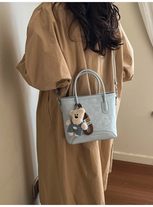 Light blue bucket bag detail with adjustable strap and cute teddy bear charm accessory