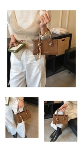 Detail of vintage brown tote bag with beaded tassel charm and decorative front text