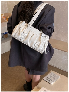 Detail of white patent leather shoulder bag with vintage buckles and punk rivets