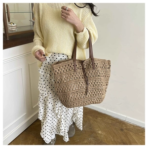 Close-up of woven straw tote bag with brown leather handles and drawstring closure details