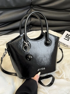 Glossy black patent leather bucket bag with silver logo and chic wrinkled texture