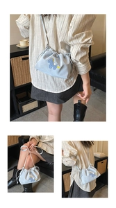 Detail of light blue drawstring bucket bag featuring exquisite donkey embroidery