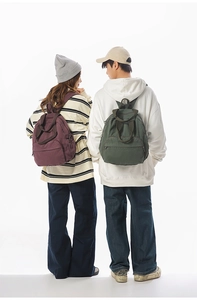 Rear view of models wearing large capacity burgundy and dark green canvas backpacks
