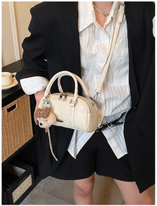 Detail of cream Boston bag with bear charm and silver hardware shown in lifestyle setting