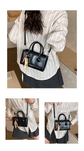 Three-way view of a black baguette bag with top handles and a colorful wooden bead tassel