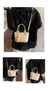 Detail of a beige bucket bag with wooden bead charm and embossed logo on fine texture