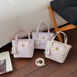 Detailed shot of quilted plaid shoulder bags in pink, purple and beige with rabbit charms