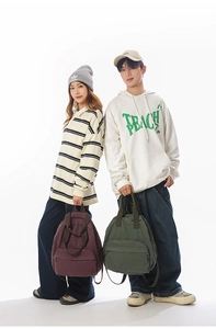 Detail of vintage canvas backpacks in burgundy and olive green with front zipper pocket
