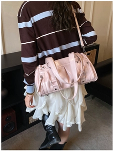 Pink patent leather Boston bag featuring multiple zippers and adjustable shoulder straps