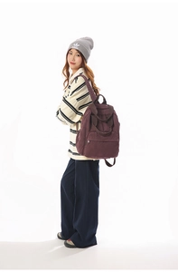 Close-up of a burgundy canvas backpack with front zipper and double handles for travel