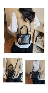 Detail of black leather bucket bag with decorative wooden beads and gold lettering