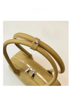 Detail of round padded leather handles with metal snap closure and dual silver zippers
