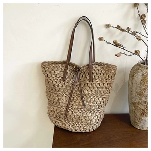 Detail of hand-woven straw tote with premium brown leather straps and visible stitching