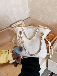 Minimalist white quilted shoulder bag with chain straps and a brown plush bear charm