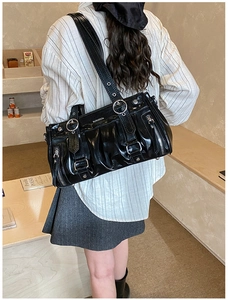 Chic black pleated shoulder bag with silver buckles shown on a model's shoulder