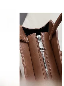 Macro detail of smooth silver metal zipper and fine stitching on a brown leather tote bag