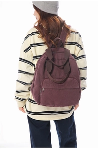 Deep purple canvas backpack shown on a model to demonstrate capacity and size
