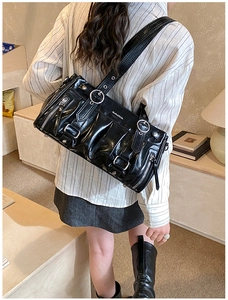 Close-up of black pleated cloud bag with silver ring buckle and adjustable strap detail