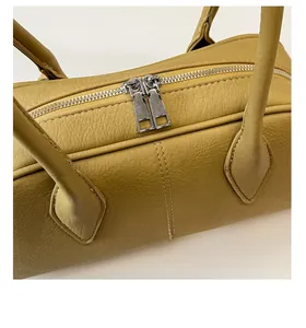 Detail view of mustard yellow vintage pillow bag with silver zippers and lychee leather texture
