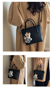 Detail of black leather bucket bag with cute teddy bear charm and adjustable strap