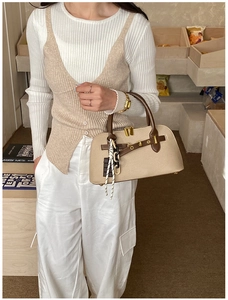 Détail du sac beige avec poignées en cuir marron et boucles métalliques dorées élégantes