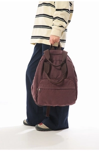 Detailed shot of dark wine red canvas backpack with front zipper pocket and sturdy handle