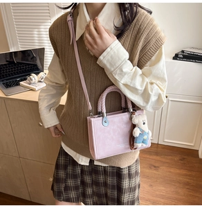Pink crossbody bag with braided handle, cute bear charm, and adjustable slim strap