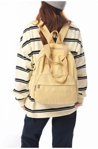 Detailed view of yellow canvas backpack showing large main compartment and front pocket