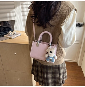 Detail of pink PU leather square crossbody bag featuring a cute teddy bear charm
