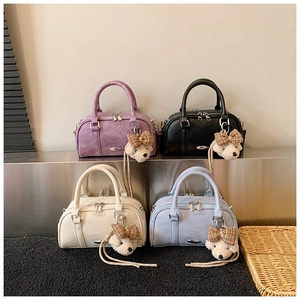Detail of four colorful PU leather Boston bags with ripple texture and cute teddy bear charms