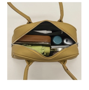 Top view of spacious mustard yellow boston bag interior with daily essentials and pockets