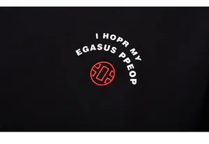 Detail of white graphic lettering and red embroidered logo on black streetwear sweatshirt