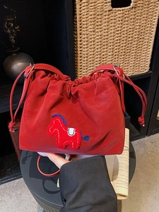 Red cloud bucket bag with embroidered horse detail and drawstring on vintage background