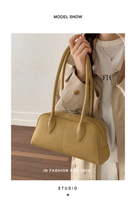 Close-up of mustard yellow leather boston bag with lychee texture and long top handles