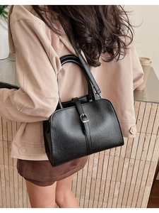Detailed view of a vintage black leather handbag featuring a stylish metal clasp buckle