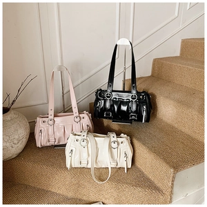 Close-up of pleated cloud bags in pink, black, and white with silver ring accents