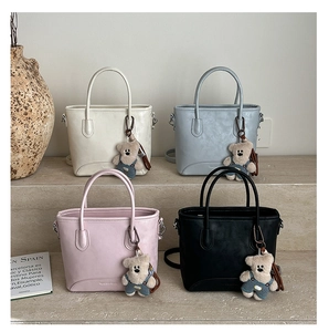Macro shot of stylish tote bags in four colors with cute teddy bear bag charms